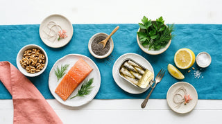 Flat lay of salmon, sardines, walnuts, chia seeds and lemon on a white surface