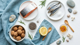 Overhead flat lay of salmon, sardines, walnuts, chia and amber softgels on a white surface