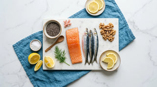 Flat lay of salmon, sardines, walnuts, chia seeds, and lemon on white marble