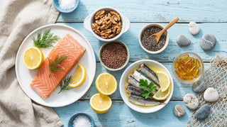 Coastal flat lay of salmon, sardines, walnuts, chia seeds, and amber softgels representing omega-3 sources