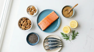 Flat lay of salmon, sardines, walnuts, chia seeds, and lemon on a white surface
