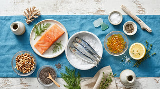 Flat lay of omega-3 food sources and amber softgels on an ocean-blue and white surface