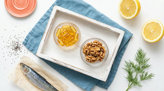 Premium flat lay of omega-rich foods and amber softgels arranged on a bright white surface with ocean-blue accents