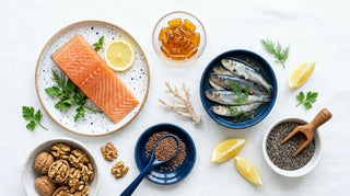Flat lay of salmon, sardines, walnuts, chia seeds, lemon, and amber omega-3 softgels on white