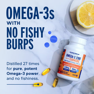 A bottle of Omega-3 2100 MG with Turmeric, two capsules, and a lemon slice rest on a marble surface.